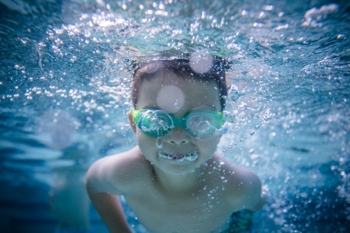 Mixed race boy swims and plays in a backyard pool