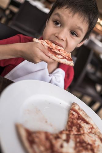 Mixed race boys eating pizza and pasta at a suburban Italian restaurant - Australian Stock Image