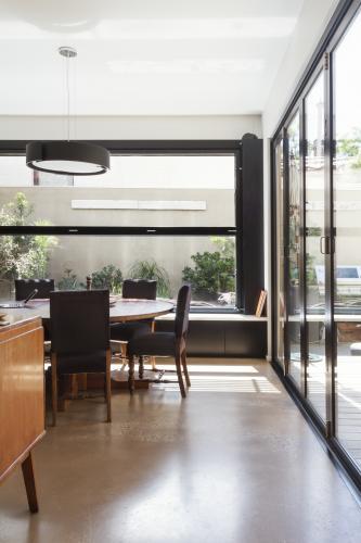 Modern dining room with concrete floor and glass bi fold doors and garden outlook - Australian Stock Image