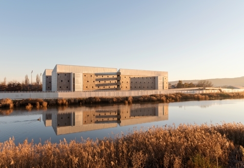 Modern exterior of a multi level building on the side of the Tamar River, the building is reflected