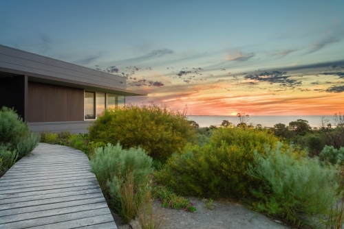 modern house overlooking the ocean at sunset - Australian Stock Image