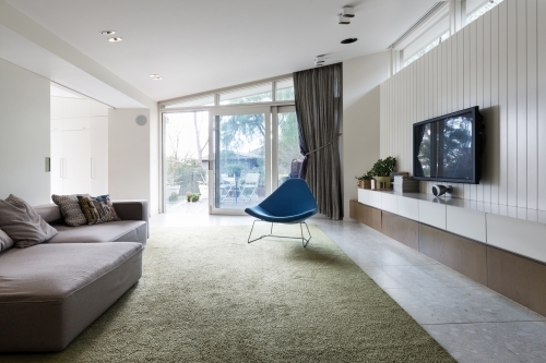 Modern living room with blutterfly angled roofline and wall hung cabinets and shelf - Australian Stock Image