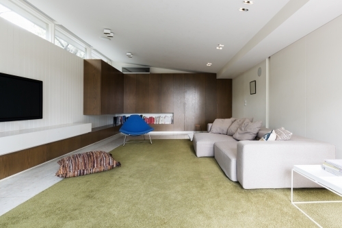Modern living room with custom walnut cabinetry and large green wool rug - Australian Stock Image