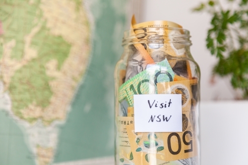 Money jar with visit NSW on it near map of Australia - travel concept - Australian Stock Image