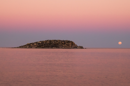 Moon going down over water with rocky island in foreground, Victor Harbour, South Australia - Australian Stock Image