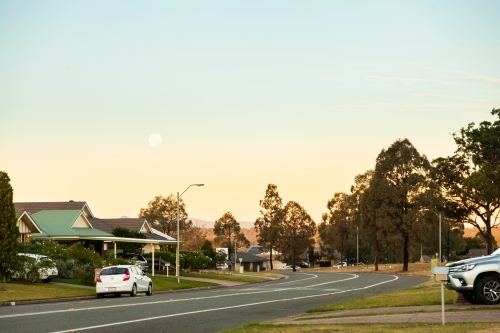 Moon in sky at dusk over suburban street in singleton - Australian Stock Image