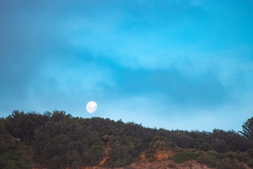 Moon rising over cliff at Redhead Beach, Newcastle NSW - Australian Stock Image