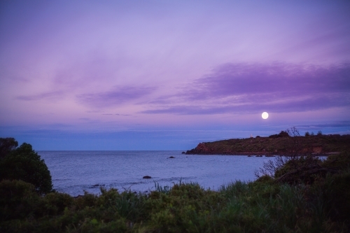 Moon rising over coastal landscape