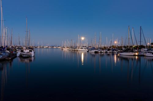 Moon rising over yachts in marina with reflections in water - Australian Stock Image