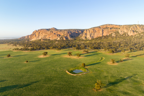 Morning light on Mount Arapiles rising above green farmland and a small dam. - Australian Stock Image