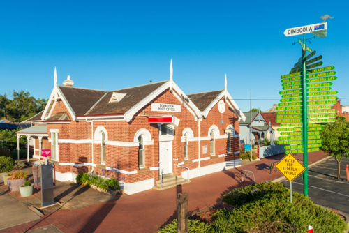 Morning sun on the historic Dimboola Post Office with its red brick facade and signpost - Australian Stock Image