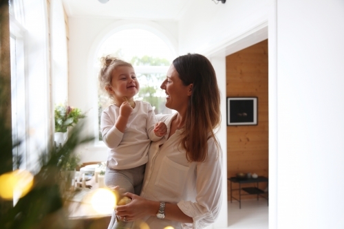 Mother and daughter at home with Christmas tree and lights - Australian Stock Image