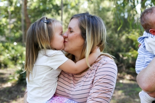 Mother and daughter cuddling and kissing - Australian Stock Image