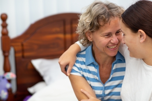 Mother and daughter having close moment in bedroom - Australian Stock Image