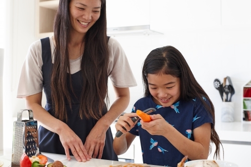 Mother and daughter having fun in kitchen together preparing healthy lunch - Australian Stock Image
