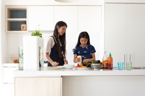 Mother and daughter in kitchen cooking together - Australian Stock Image