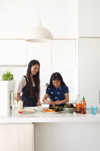 Mother and daughter in kitchen cooking together - Australian Stock Image