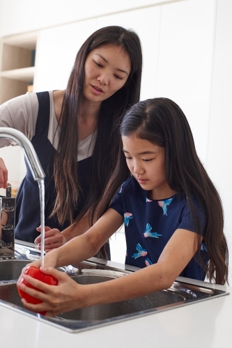 Mother and daughter in kitchen together preparing lunch - Australian Stock Image