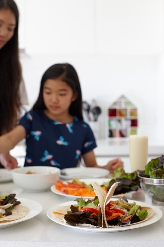 Mother and daughter in kitchen together preparing lunch - Australian Stock Image
