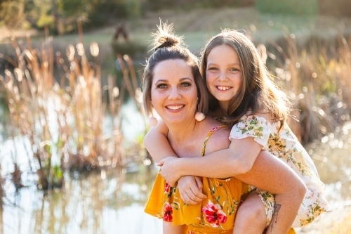 Mother and daughter piggyback ride - Australian Stock Image