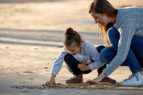 Mother and daughter playing on beach together - Australian Stock Image