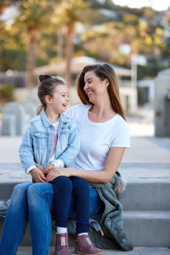 Mother and daughter sharing time laughing at beach promenade