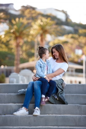 Mother and daughter sharing time laughing at beach promenade - Australian Stock Image
