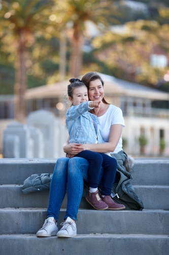 Mother and daughter sharing time laughing at beach promenade - Australian Stock Image