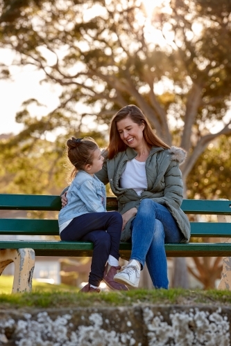 Mother and daughter sharing time laughing at park - Australian Stock Image