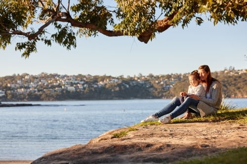 Mother and daughter sharing time together at headland over ocean - Australian Stock Image
