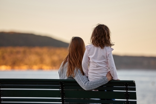 Mother and daughter sharing time together on sunset at beach - Australian Stock Image