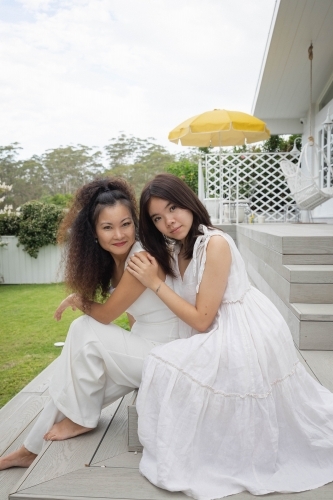 Mother and daughter sitting together on backyard steps - Australian Stock Image