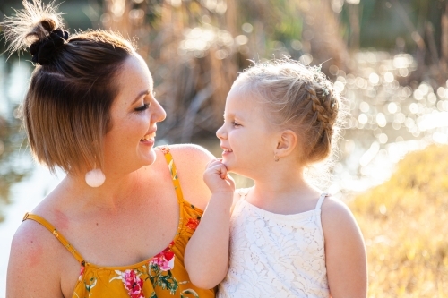 Mother and daughter smile at one another outside - Australian Stock Image