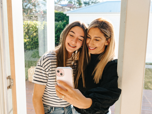 Mother and daughter taking selfies in the doorway. - Australian Stock Image
