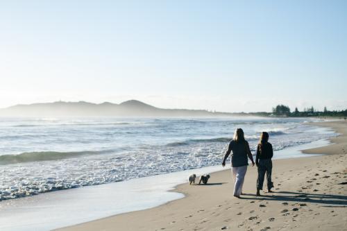 Mother and daughter walking on the beach with dogs