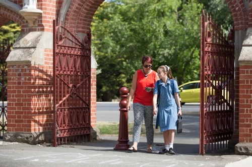 mother and daughter walking through gates of a private girls school - Australian Stock Image