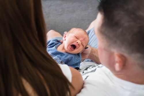 Mother and father holding crying baby boy - Australian Stock Image