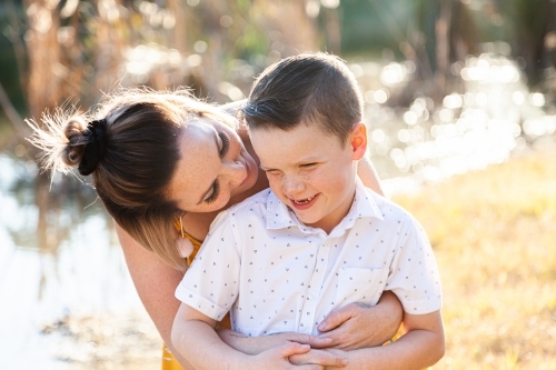 Mother and son hug outside beside dam - Australian Stock Image