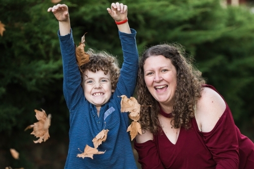 Mother and son playing in autumn leaves - Australian Stock Image