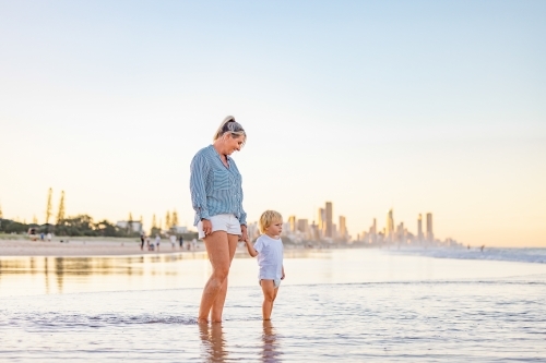 Mother and son playing in shallow water on Gold Coast beach - Australian Stock Image