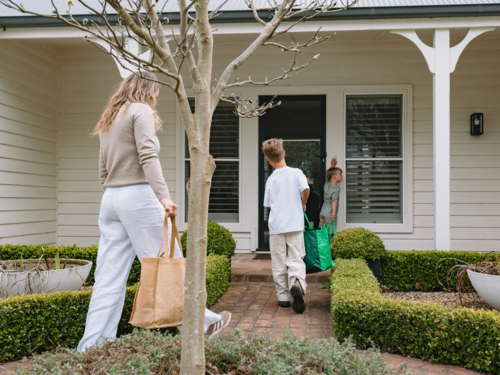 Mother and son walking on a brick pathway towards the house - Australian Stock Image