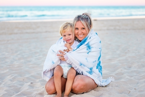 Mother and son wrapped in beach towel