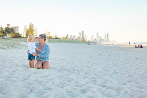 Mother and toddler son embracing on the sand of Gold Coast beach - Australian Stock Image