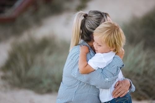 Mother and toddler son hugging on the beach - Australian Stock Image