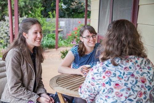 Mother and two teen daughters sitting together talking - Australian Stock Image