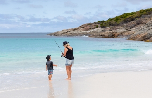 mother and young son fishing on white sand beach - Australian Stock Image