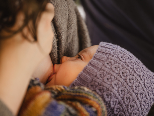 Mother breastfeeding baby wearing beanie - Australian Stock Image