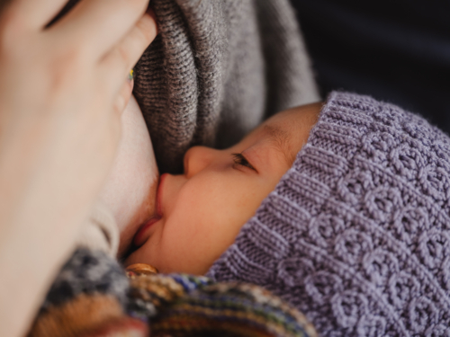 Mother breastfeeding baby wearing beanie - Australian Stock Image