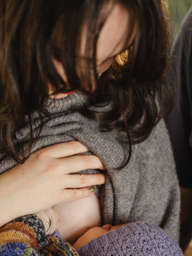 Mother breastfeeding baby wearing beanie - Australian Stock Image