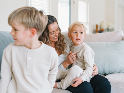 Mother cradling son on her lap while seated on the couch - Australian Stock Image